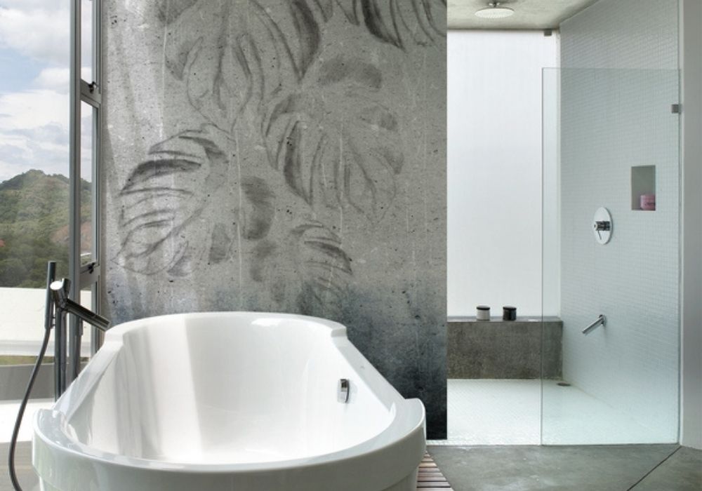 Modernes Badezimmer mit freistehender Badewanne, großer Dusche und Tapete in Betonoptik – stilvolle Badgestaltung vom Wohnatelier im Schlossquartier in Eisenstadt, Burgenland.